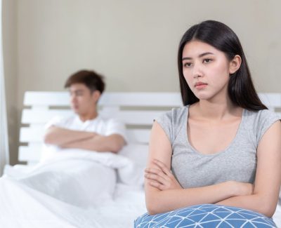 Selective young wife sitting on bed with feel bored about her husband  , trouble Asian couple concept